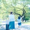 スーツケースを引き娘と手をつないで歩くCoharu